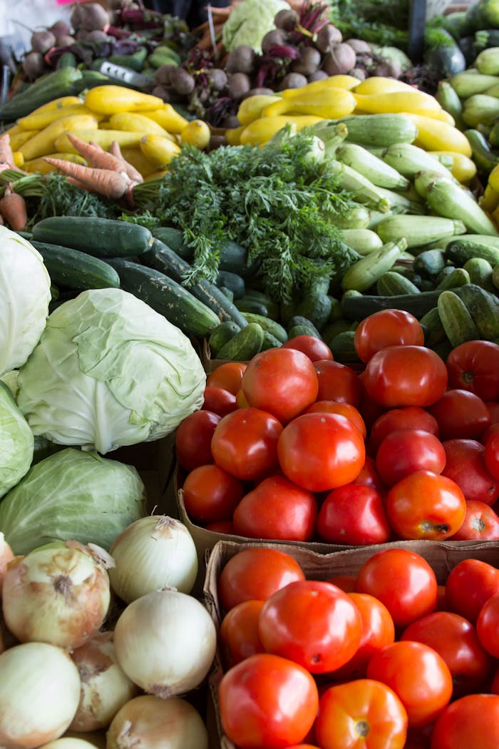 contact-img Vibrant display of organic vegetables including tomatoes, cabbages, and more at a North Carolina market.